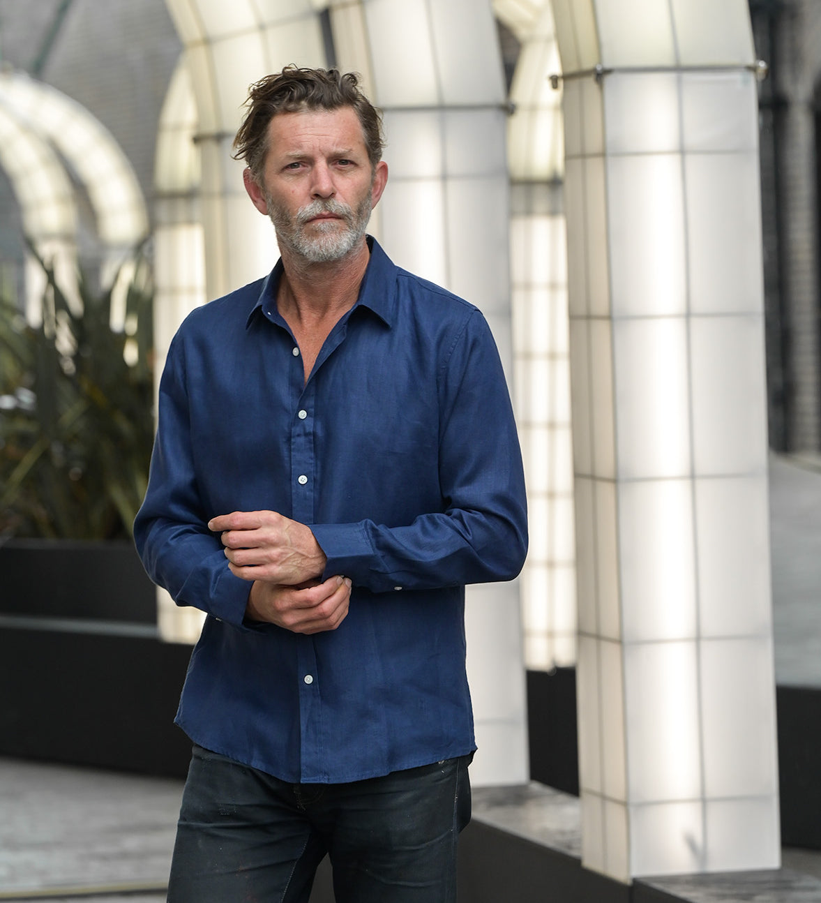 man wears navy blue hemp shirt whilst doing up cuffs