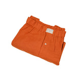 Neatly folded orange hemp boxer shorts with a label on a white background