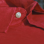 Close-up of a red hemp fabric showing the softness of the fibres with a button on a blurred background