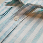 close up, detail shot of blue and white stripe shirt with main focus on high quality button fastening