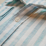 close up, detail shot of blue and white stripe shirt with main focus on high quality button fastening