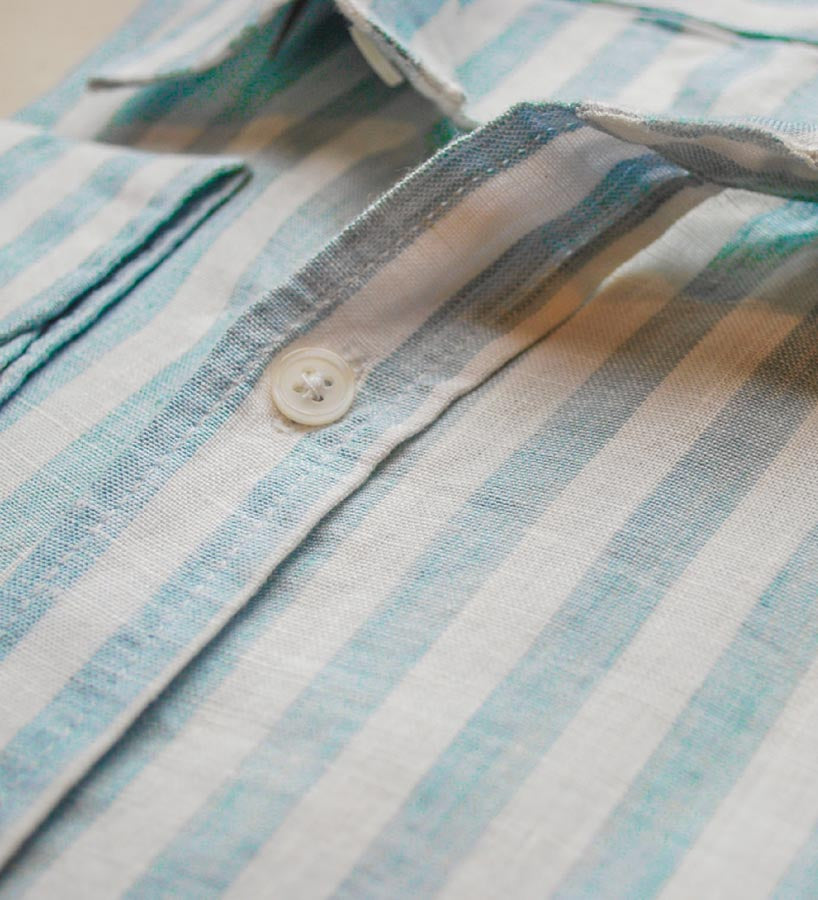 close up, detail shot of blue and white stripe shirt with main focus on high quality button fastening
