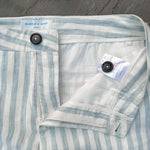 Close-up of a striped blue and white hemp short laid flat with brand labels on a grey surface