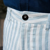 Close-up of blue and white striped hemp shorts with a button, worn with a navy shirt.