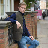 Man wearing a brown hemp nehru jacket leaning against a brick wall on a city street