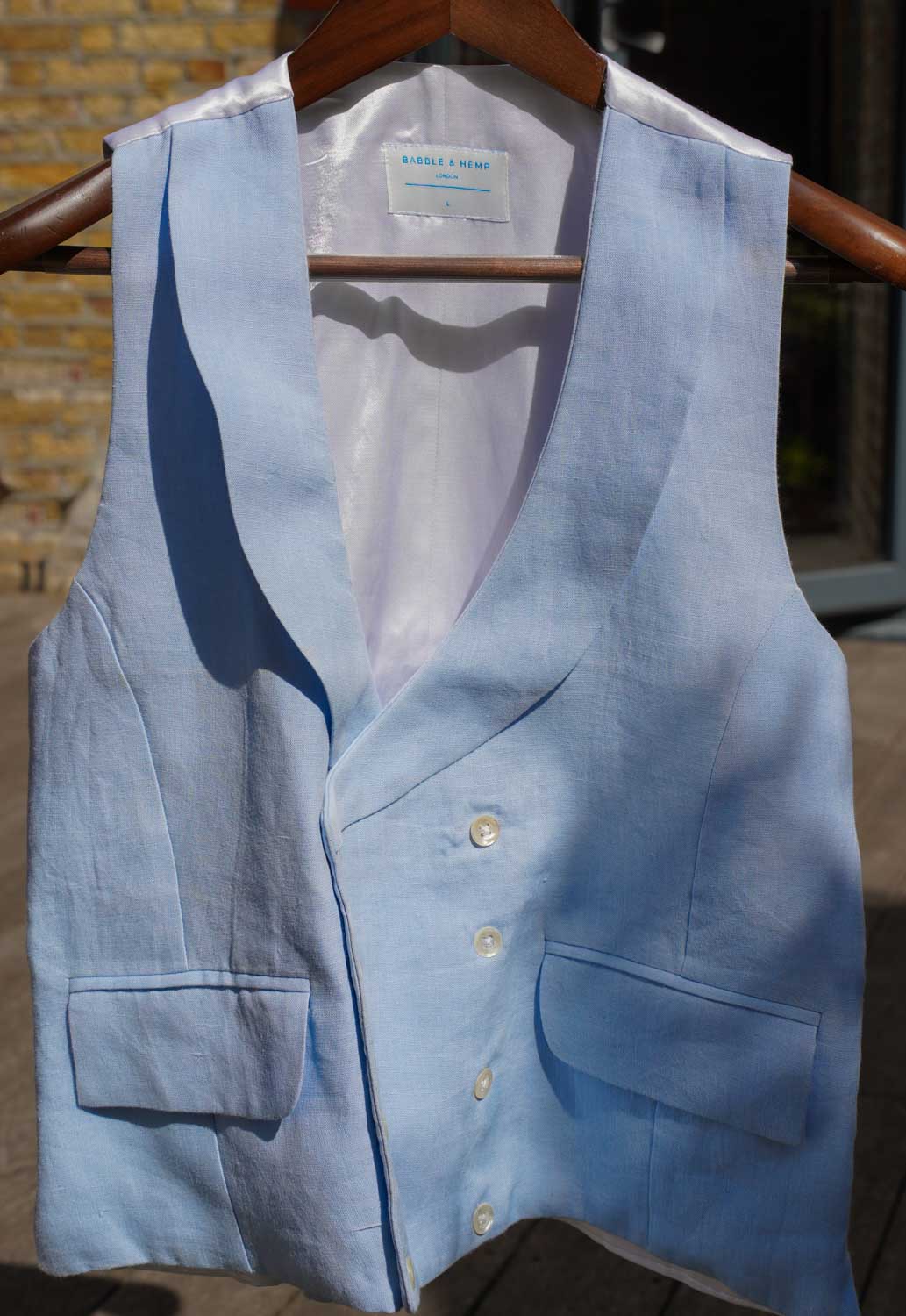 blue hemp waistcoat worn for weddings or royal ascot hangs from wooden hanger