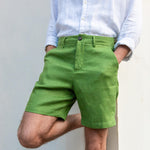 Person wearing green shorts made from hemp fabric and a white shirt against a plain background