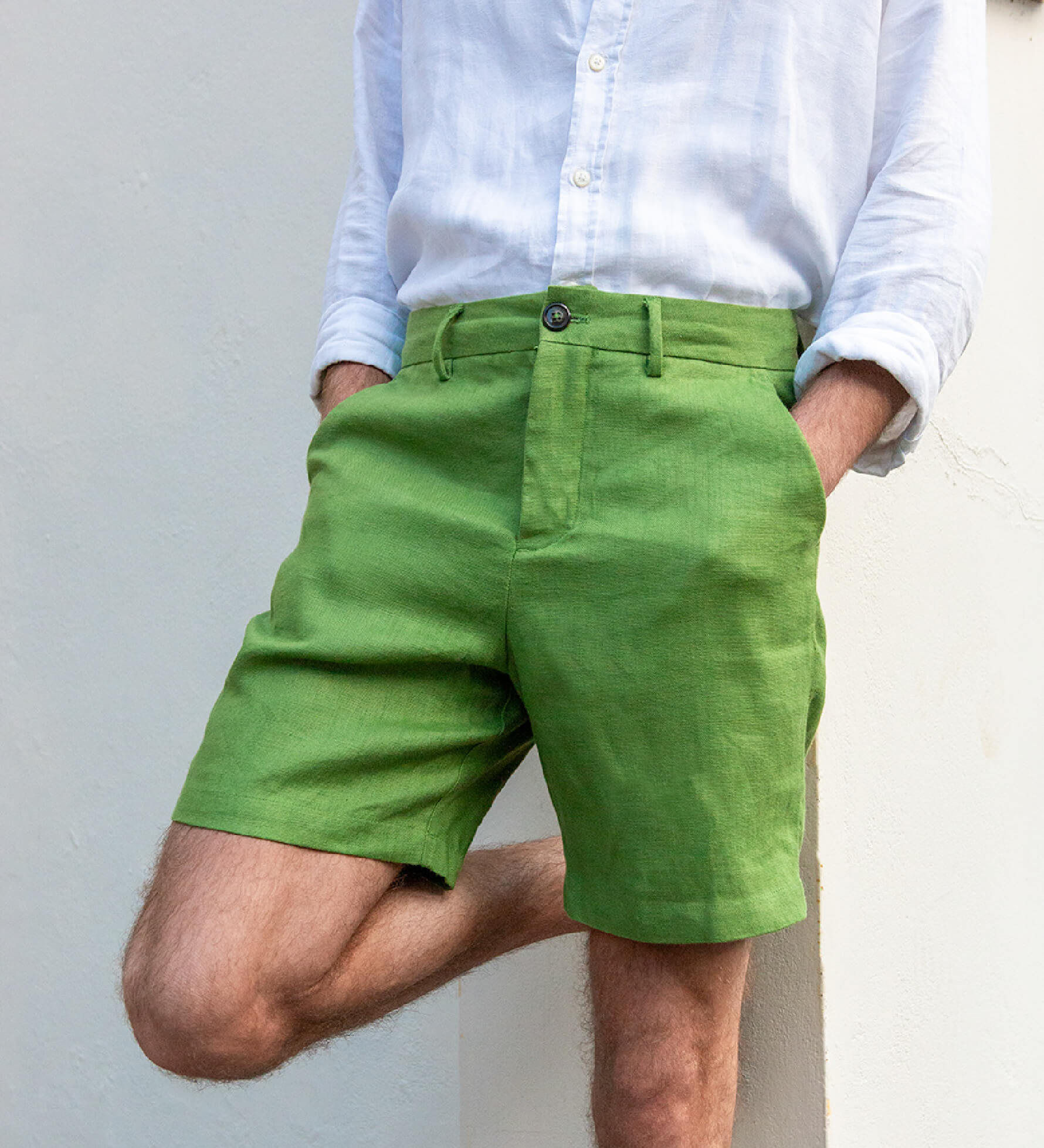Person wearing green shorts made from hemp fabric and a white shirt against a plain background