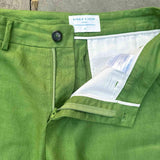 Close-up of sustainable, green hemp shorts with a brand label on a concrete surface