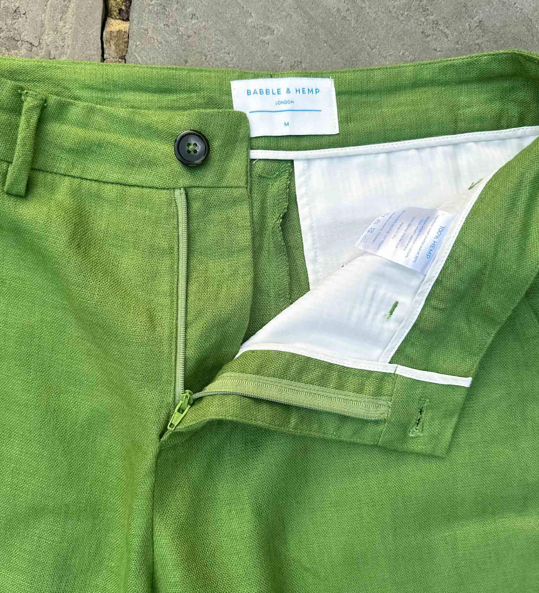 Close-up of sustainable, green hemp shorts with a brand label on a concrete surface