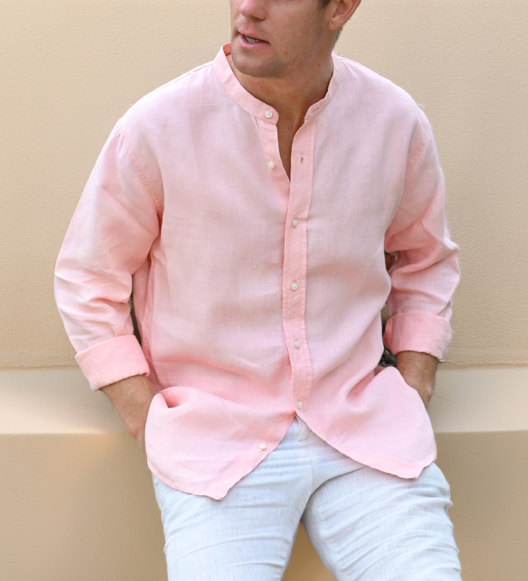 Person wearing a pink hemp shirt with mandarin collar and light blue jeans against a neutral background