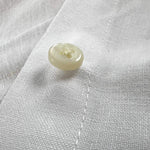 Close-up of a button on white hemp fabric demonstrating the softness of the sustainable hemp fabric