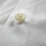 Close-up of a button on white hemp fabric demonstrating the softness of the sustainable hemp fabric