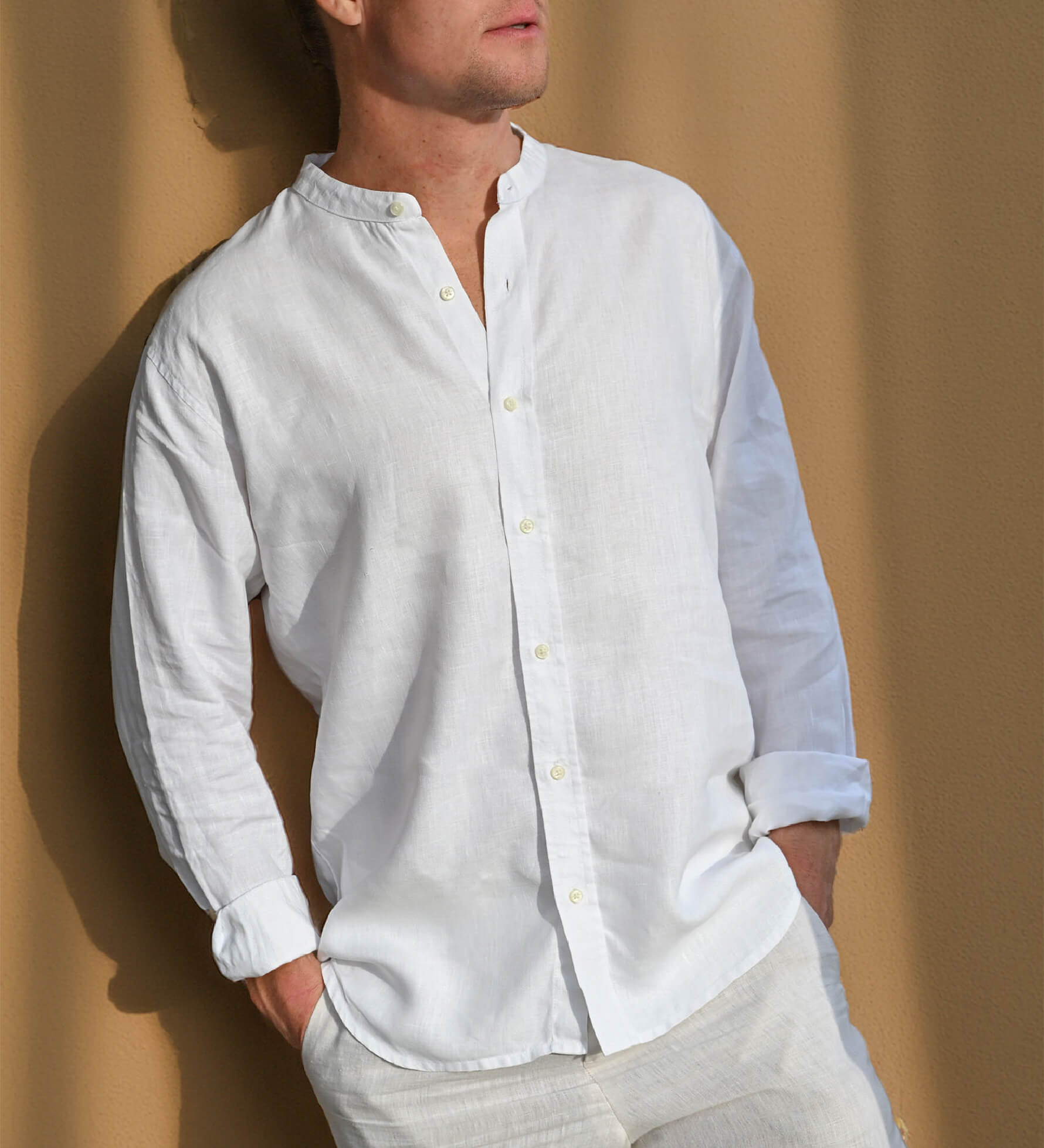 Man wearing a white collarless hemp shirt against a beige background