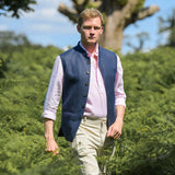 Man wearing a blue nehru jacket made from eco-friendly hemp fabric over a pink shirt in a natural setting with trees and greenery.
