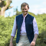 Man wearing a navy blue nehru gilet made from hemp fabric over a light pink shirt with a blurred natural background