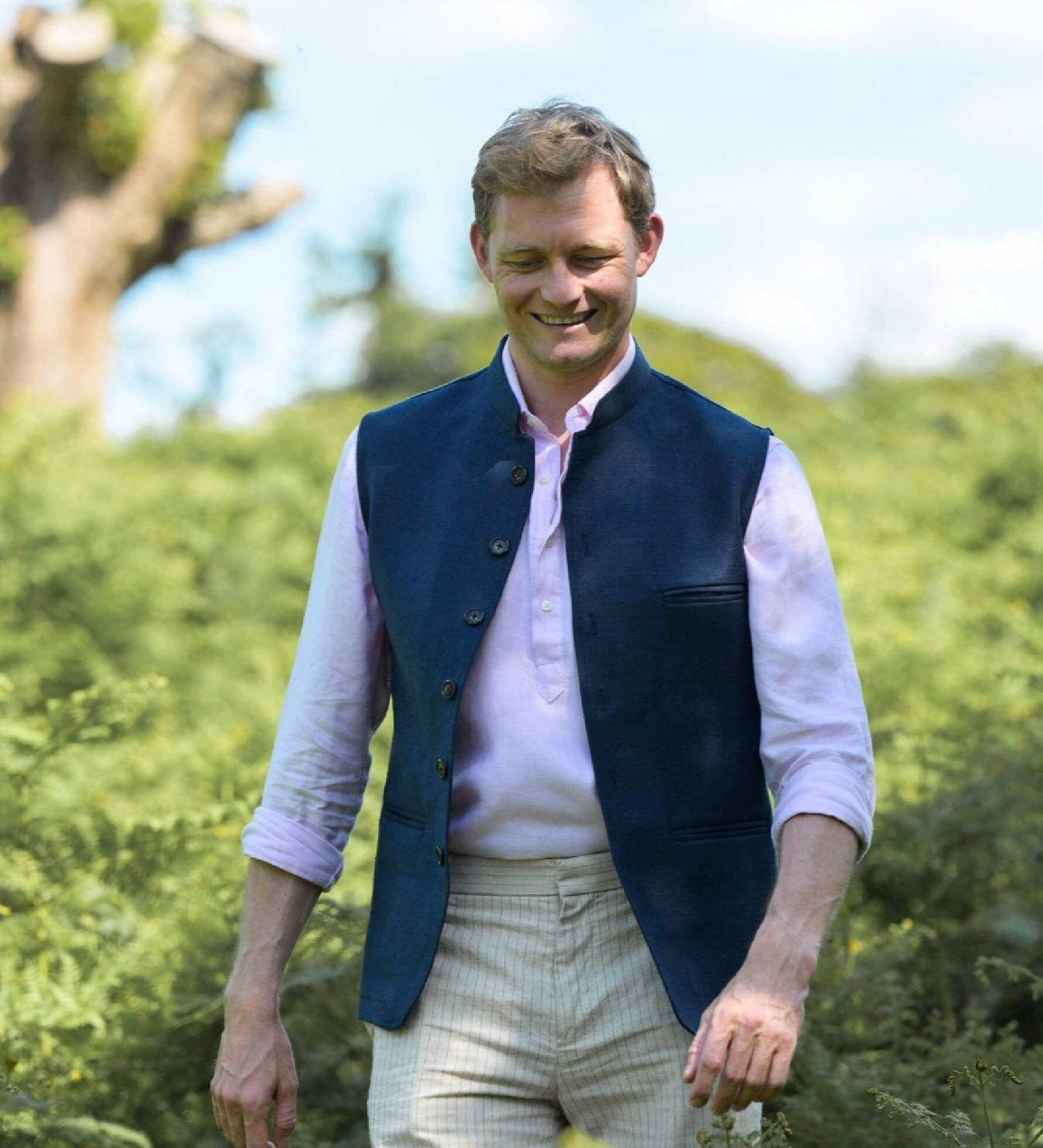 Man wearing a navy blue nehru gilet made from hemp fabric over a light pink shirt with a blurred natural background