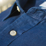 Close-up of a blue shirt showing the detail and soft texture of hemp fabric with buttons on a blurred background