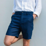 Person wearing navy blue hemp shorts and a white shirt against a plain background