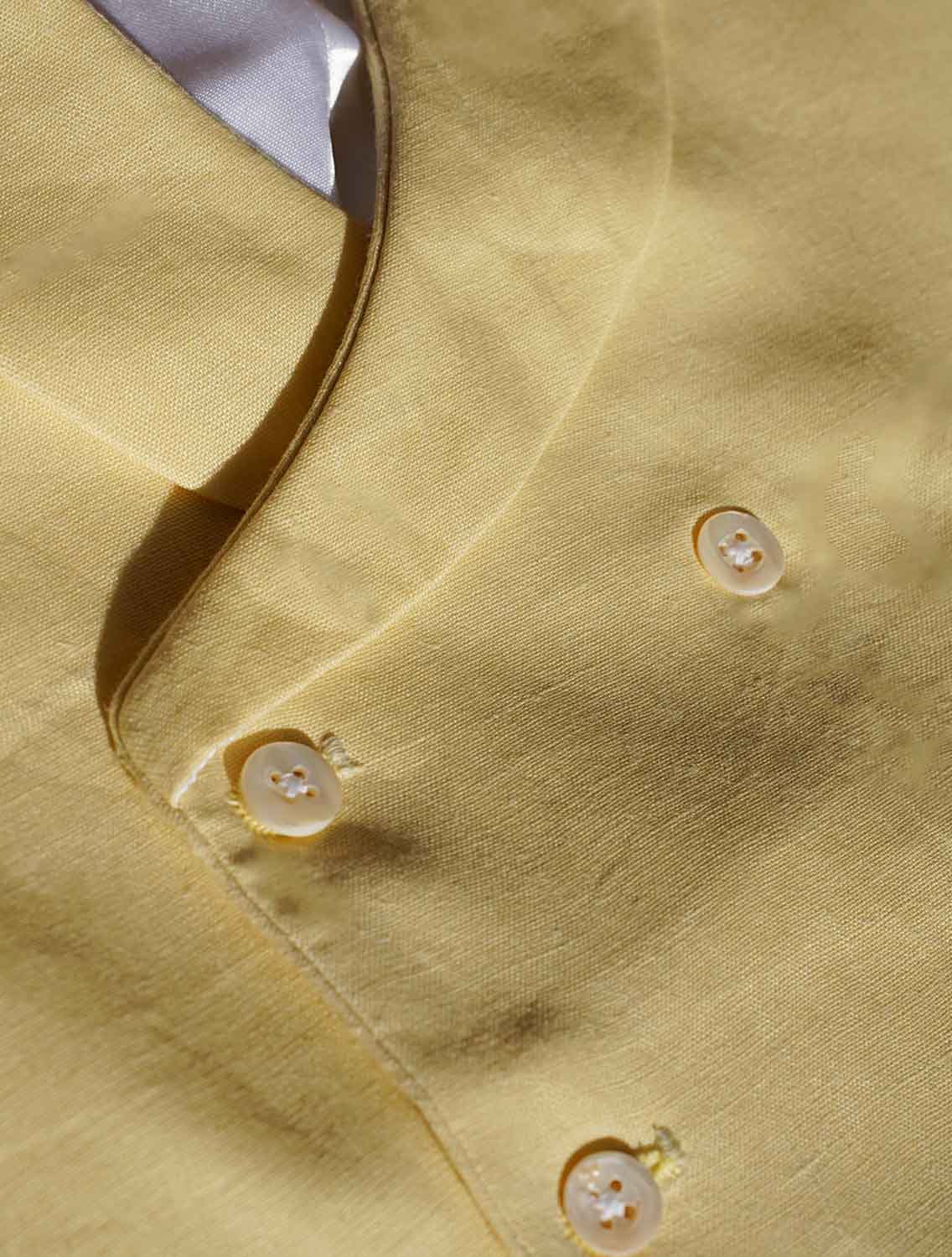 close up of yellow hemp fabric with detailed shot of buttons