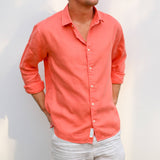 Person wearing a coral coloured button-up shirt made from sustainable hemp fabric against a plain background