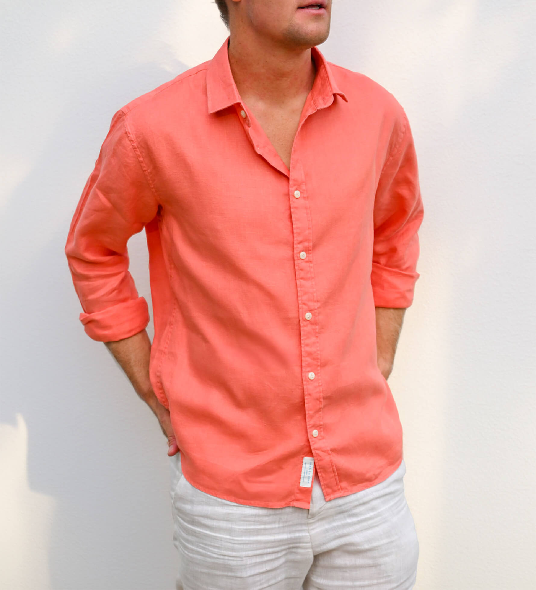 Person wearing a coral coloured button-up shirt made from sustainable hemp fabric against a plain background