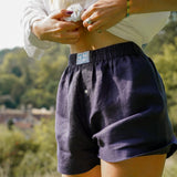 Person wearing dark navy blue hemp boxer shorts with a blurred natural background of hills dropping away behind