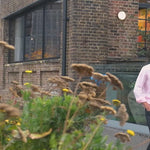 a video of a man modelling a pink hemp shirt walking near a canal