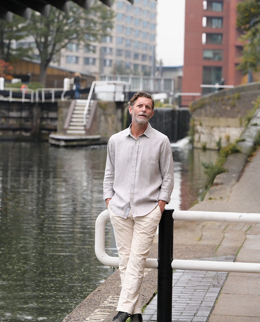 a man leans on a wall whilst wearing a sustainable hemp shirt