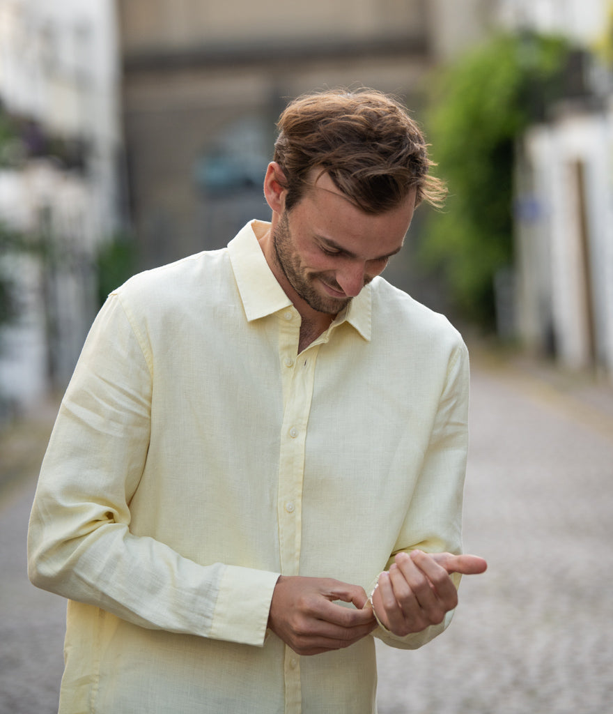 a man doing up the cuff on a yellow sustainable hemp shirt