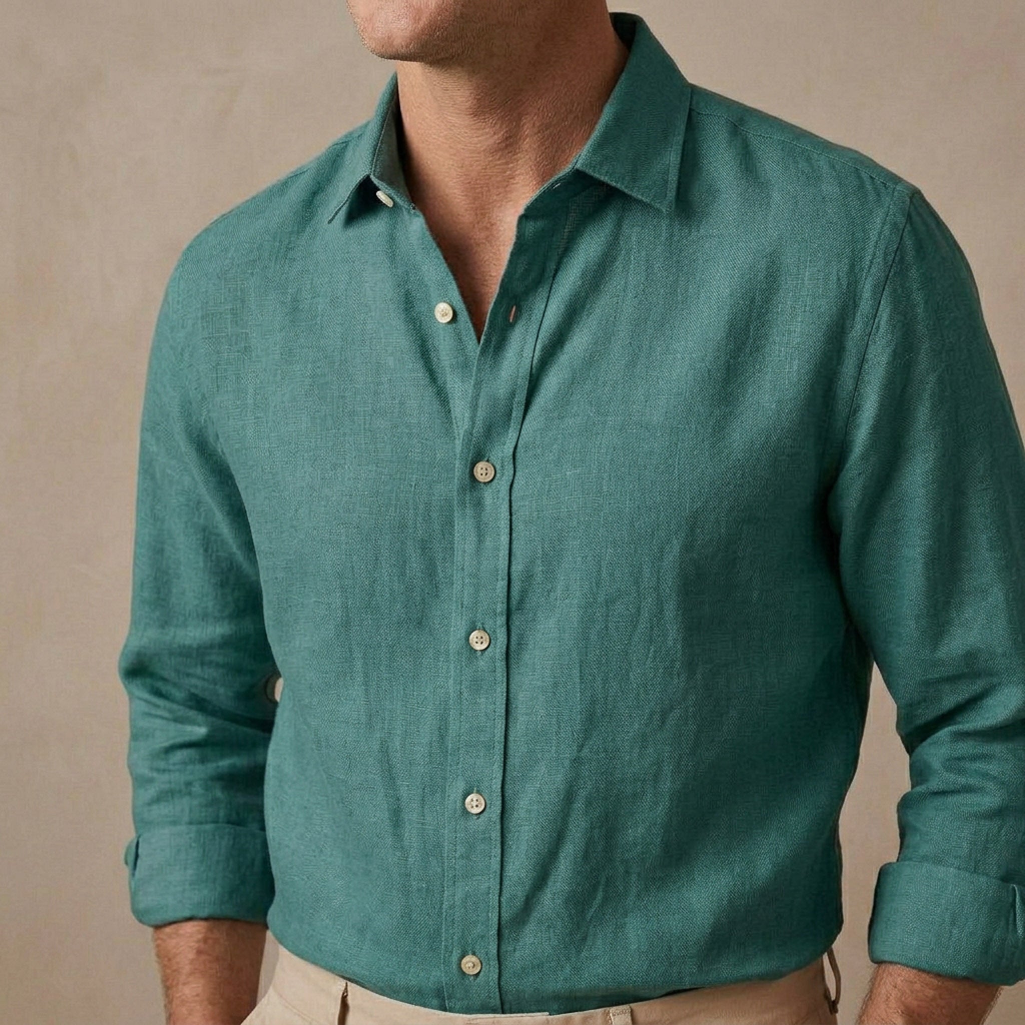 A man wearing a teal green long-sleeve heavy hemp shirt designed for autumn / winter with beige pants, shown from the neck down against a neutral beige background.