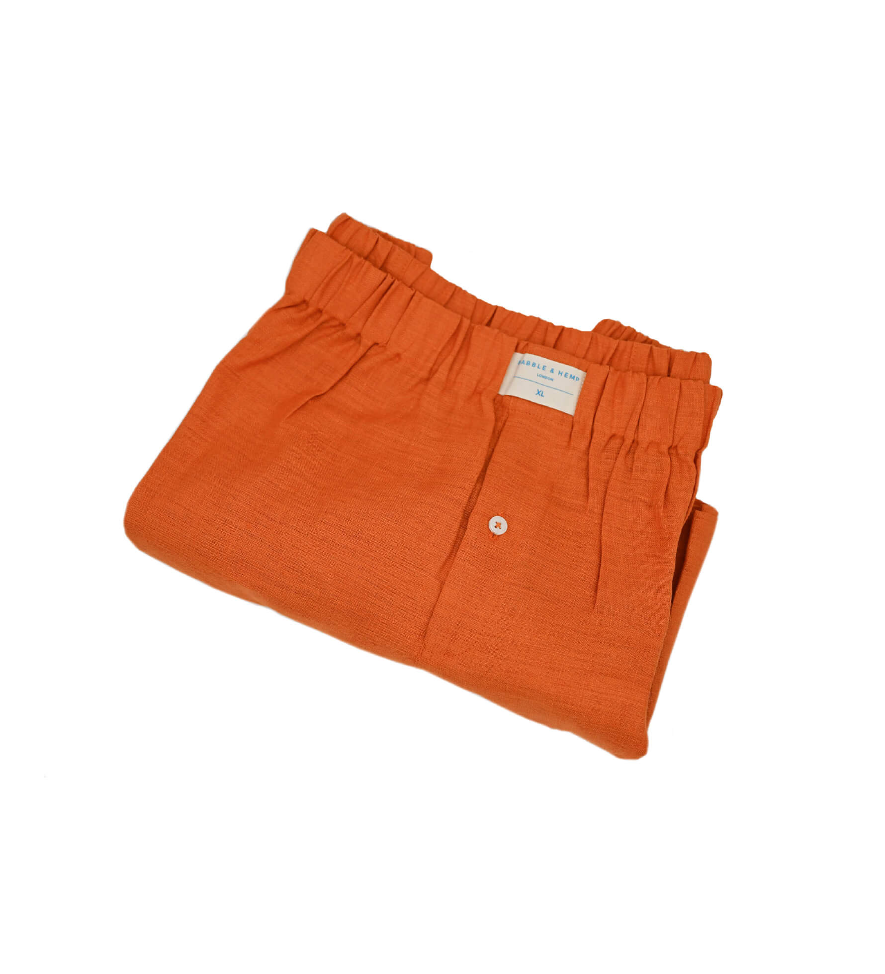 Neatly folded orange hemp boxer shorts with a label on a white background
