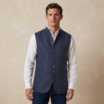 Man wearing a blue nehru gilet made from hemp fabric over a white shirt on a beige background