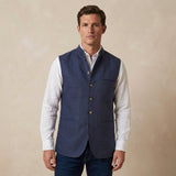 Man wearing a blue nehru gilet made from hemp fabric over a white shirt on a beige background