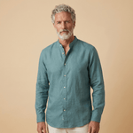 Man wearing a teal coloured hemp fabric shirt with grandad collar against a beige background
