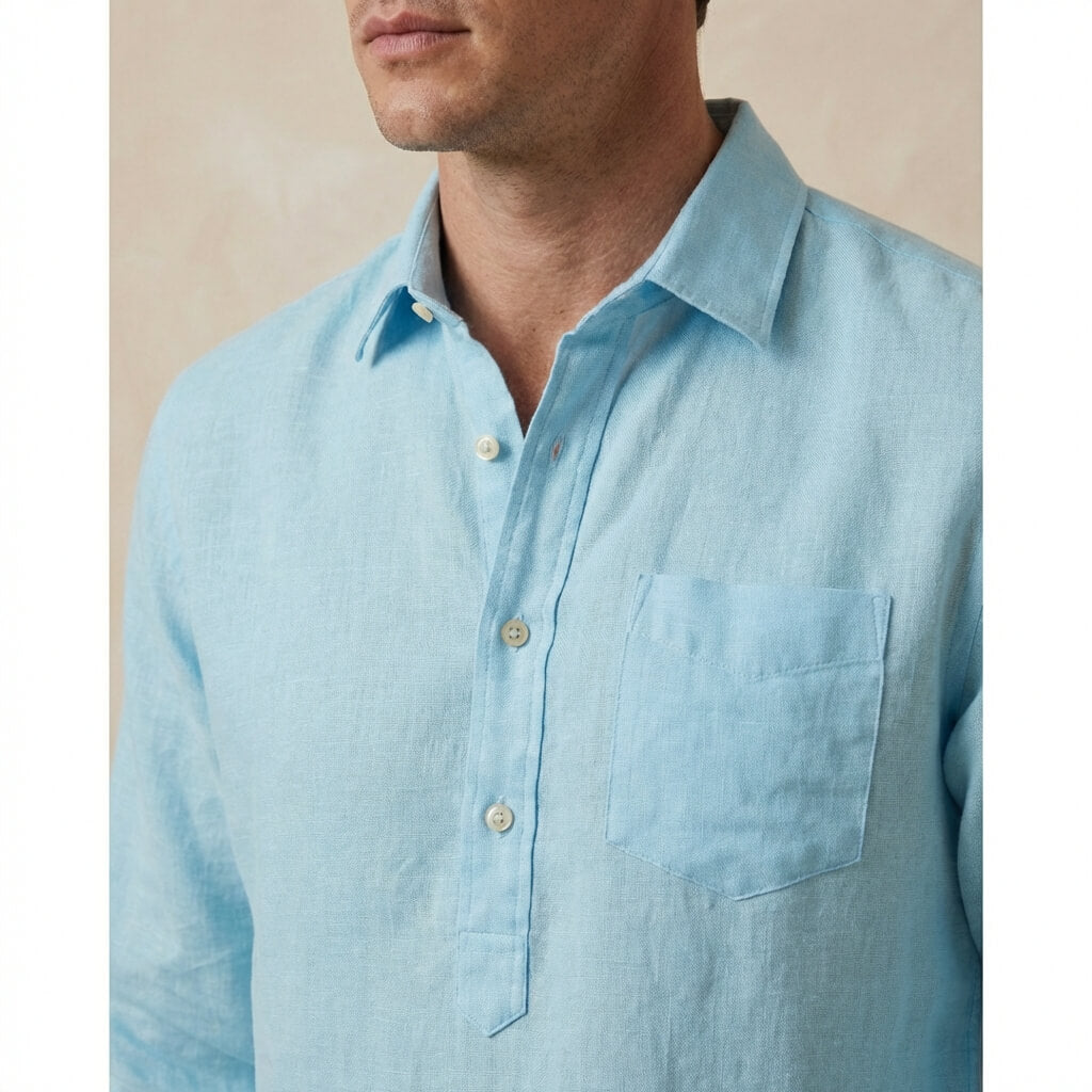 light blue button-up hemp shirt worn by a person on a beige background with focus on the chest pocket and quarter length placket