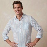 Man wearing a light blue and white striped shirt made from hemp fabric against a beige background