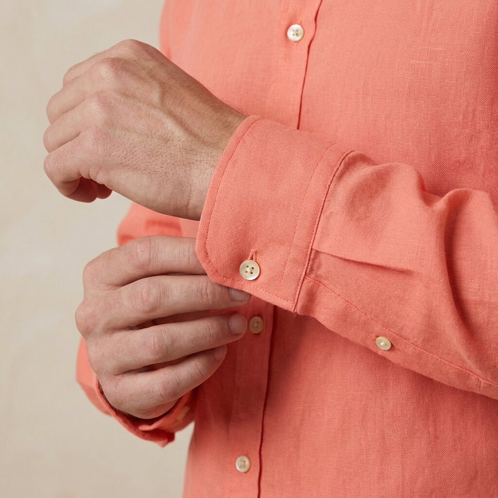 closeup shot of the cuff and button  being fastened on a hemp shirt colour coral