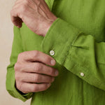 closeup shot of the cuff and button being fastened on a heavy weight hemp shirt colour green