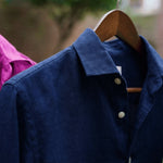 a closeup shot showing the detail and soft texture of a midnight or navy blue hemp shirt hanging on a clothesline
