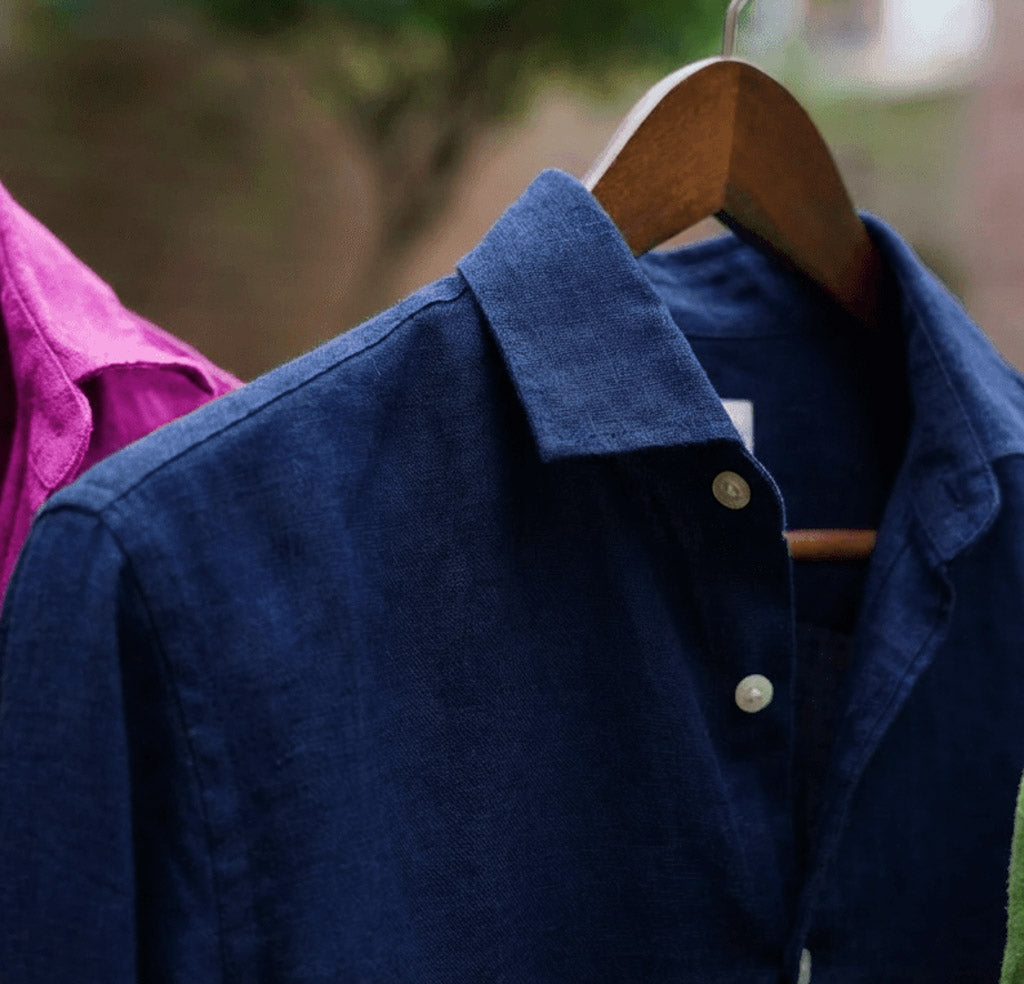 a closeup shot showing the detail and soft texture of a midnight or navy blue hemp shirt hanging on a clothesline