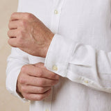closeup shot of the cuff and button being fastened on a hemp shirt colour white