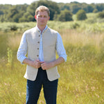 Man wearing a beige nehru gilet made from eco-friendly hemp fabric over a white shirt in a grassy field