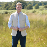 Man wearing a beige nehru gilet made from eco-friendly hemp fabric over a white shirt in a grassy field