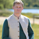 Man wearing a green jumper with cream nehru gilet outdoors with a blurred natural background