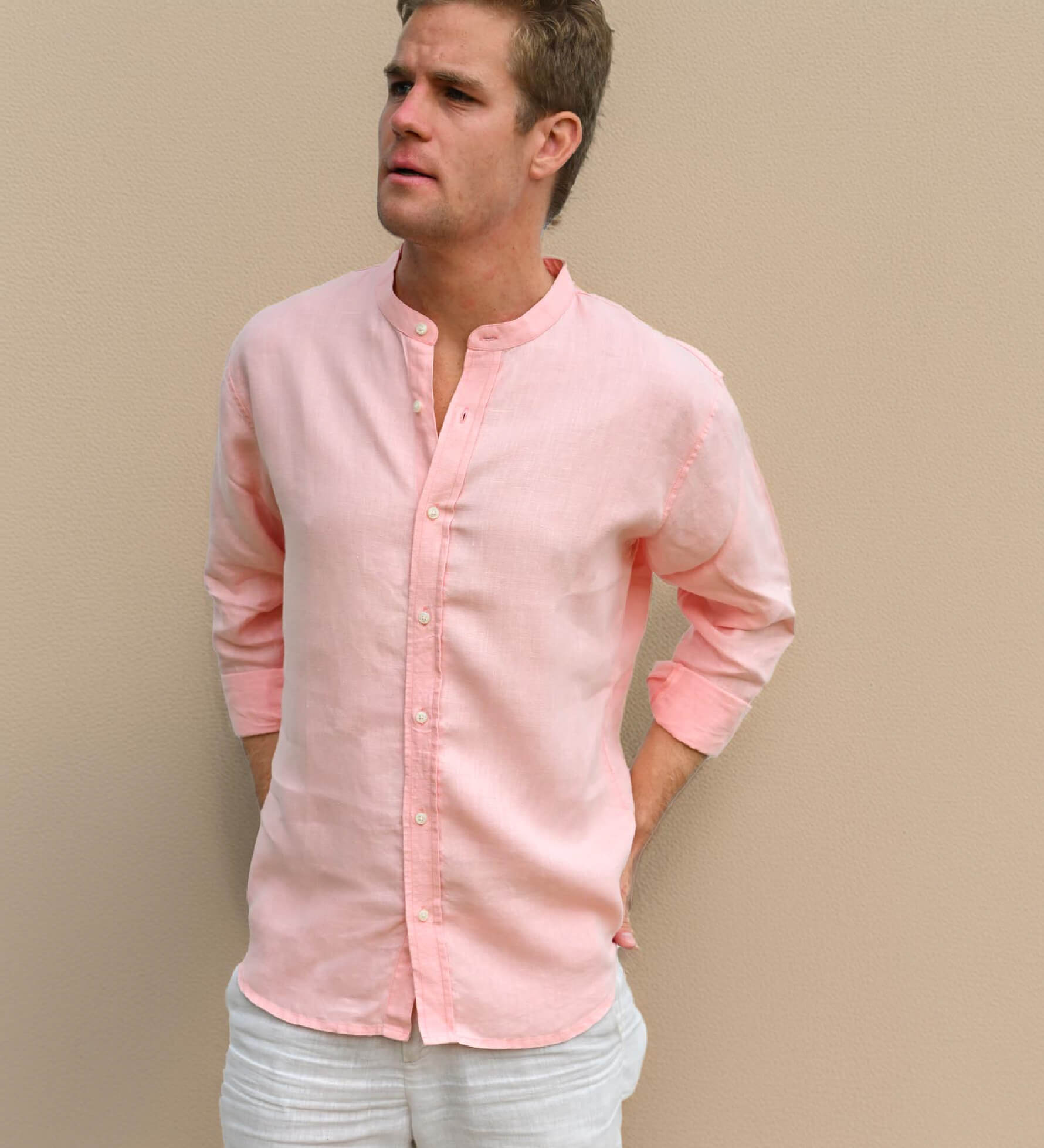 Man wearing a light peach collarless hemp shirt against a beige background