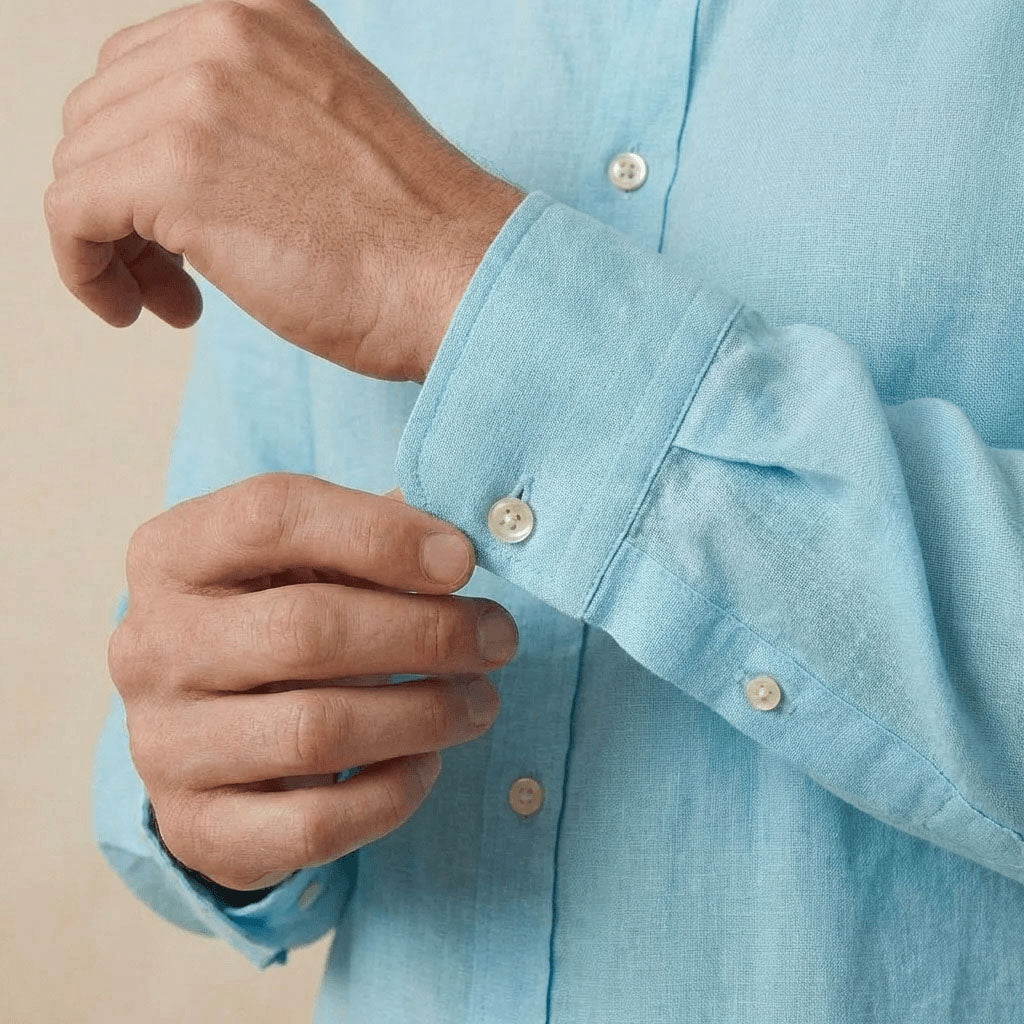 closeup shot of the cuff and button  being fastened on a hemp shirt colour light blue