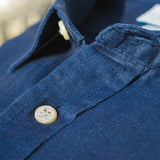 Close-up of a blue shirt showing the detail and soft texture of hemp fabric with buttons on a blurred background