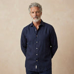 man wears dark navy heavy winter hemp shirt in front of beige backdrop