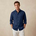 Man wearing a navy blue hemp shirt and white trousers against a beige background